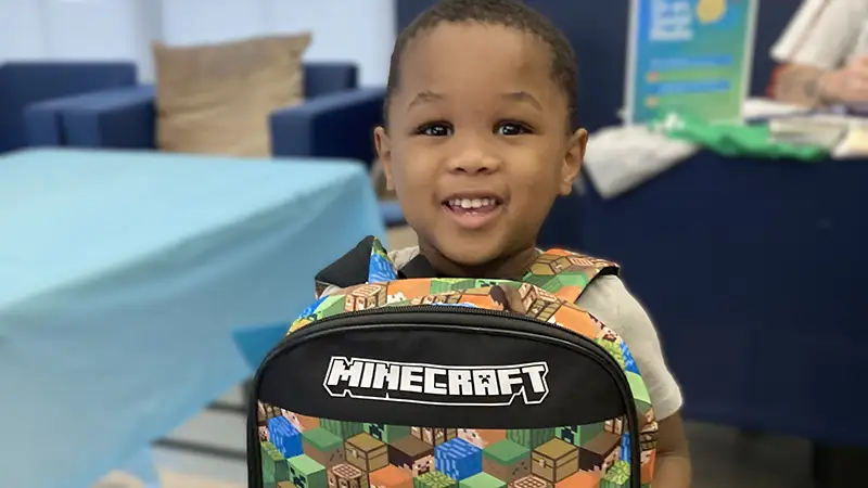 A child smiling and wearing a backpack at Operation Backpack
