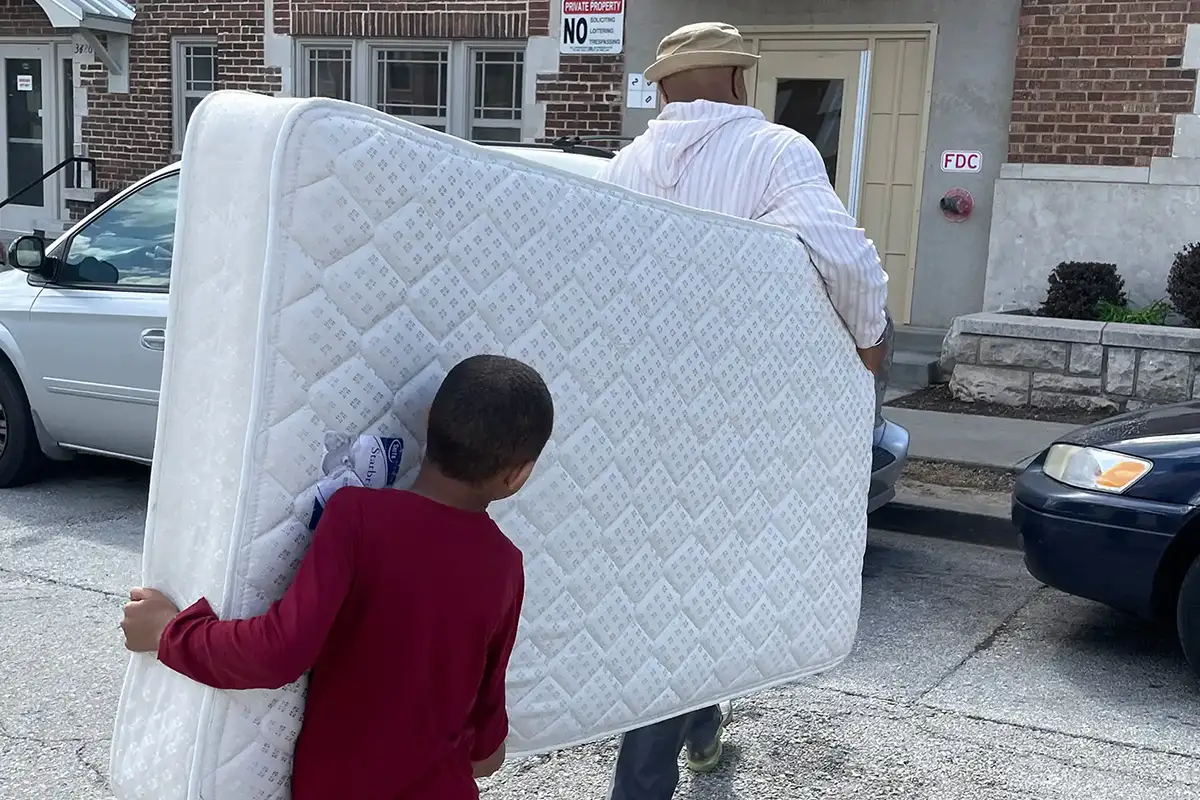 Volunteers carrying a donated mattress to help support a household