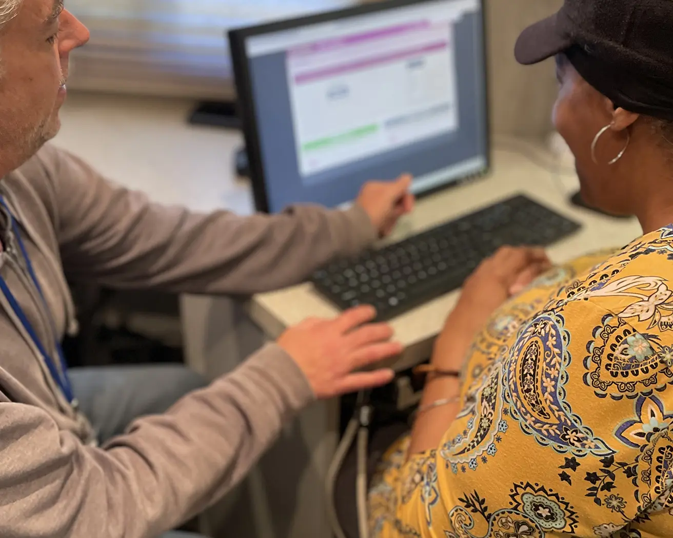 Volunteer helping an older adult with a computer.