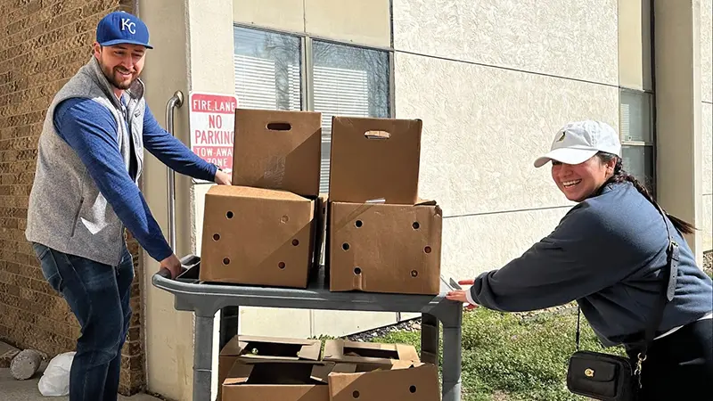 Two volunteers delivering food boxes at a Phoenix Family mobile food pantry